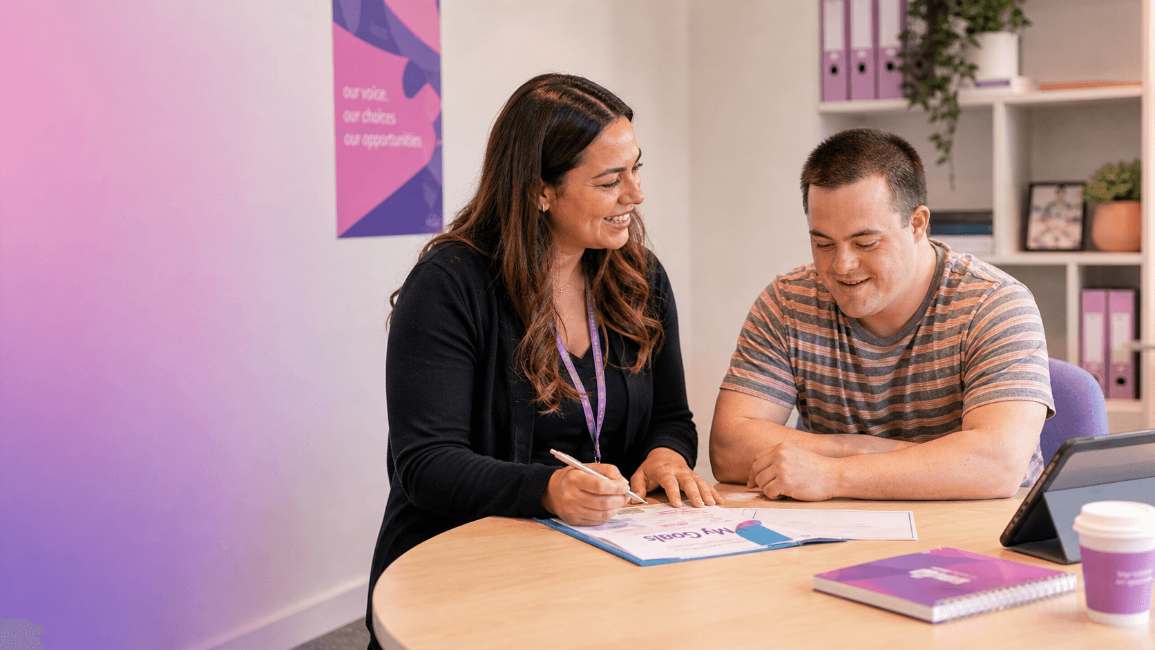 Smiling woman and man with Down syndrome review a "My Goals" document together.