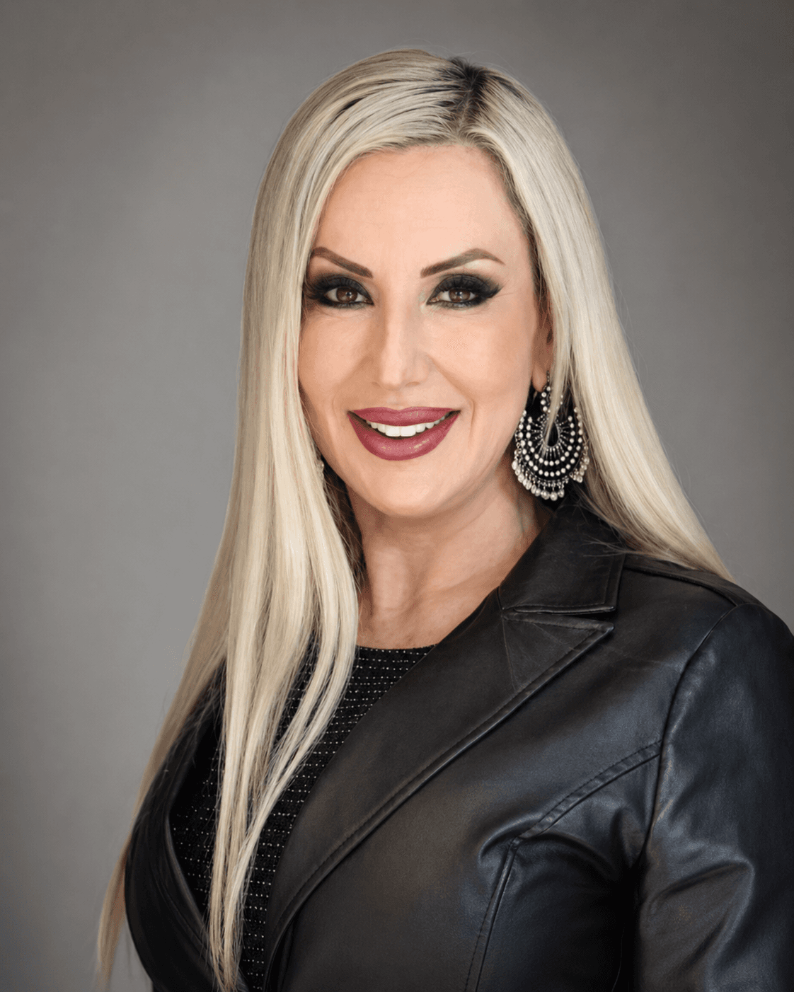Smiling woman with long blonde hair, heavy makeup, and a black leather jacket.