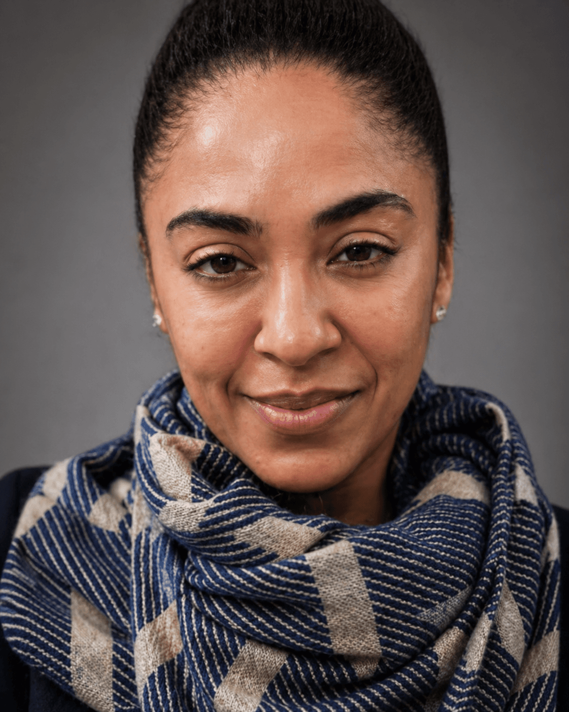 Close-up portrait of a woman with dark hair wearing a blue and tan patterned scarf.